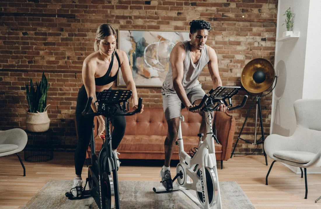 Two people on indoor cycling bikes